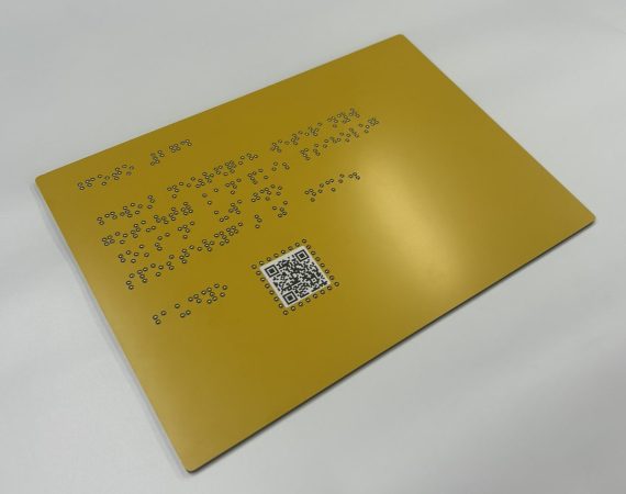Жовта тактильна табличка з кількома рядками шрифту Брайля та QR-кодом