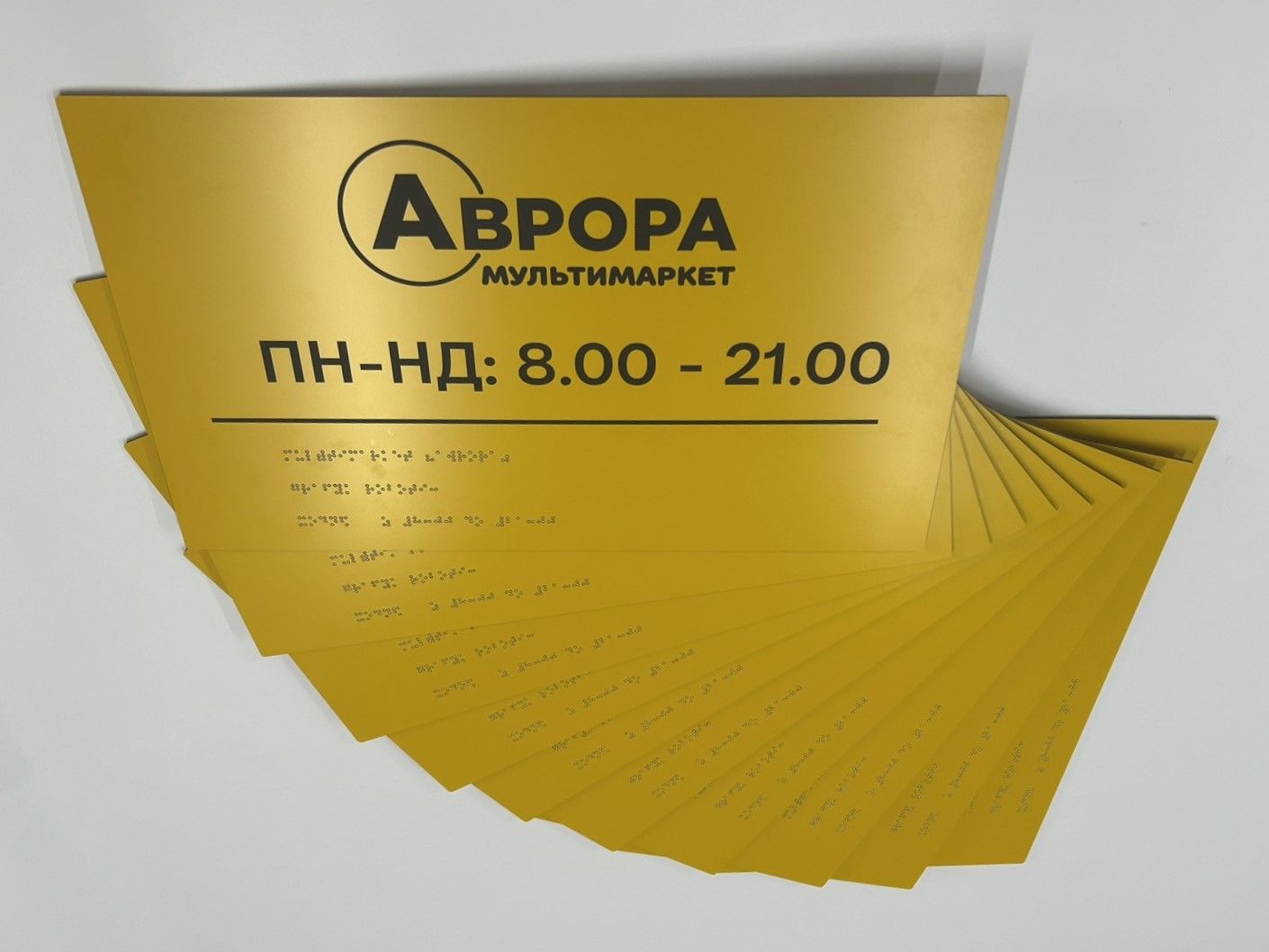 Жовті таблички «Аврора» з графіком роботи і шрифтом Брайля, розкладені віялом
